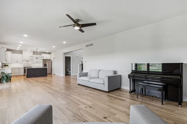 a open kitchen with stainless steel appliances granite countertop a stove a sink dishwasher a refrigerator and a dining table with wooden floor