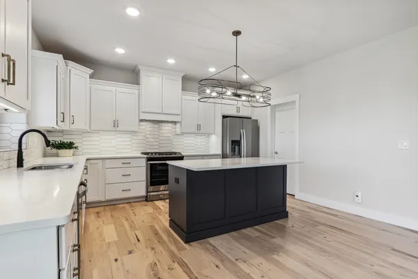 a kitchen with a sink dishwasher a stove a microwave oven and a dining table with wooden floor