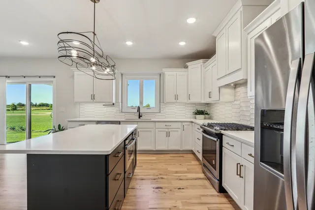 an empty room with windows and view of kitchen