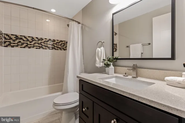 a bathroom with a sink a toilet a mirror and shower