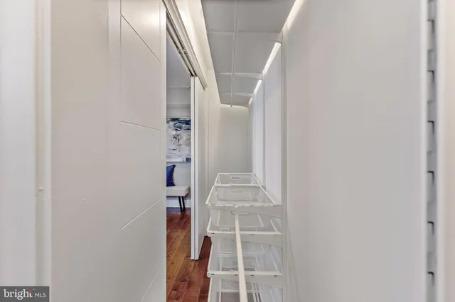 a walk in closet with wooden floor