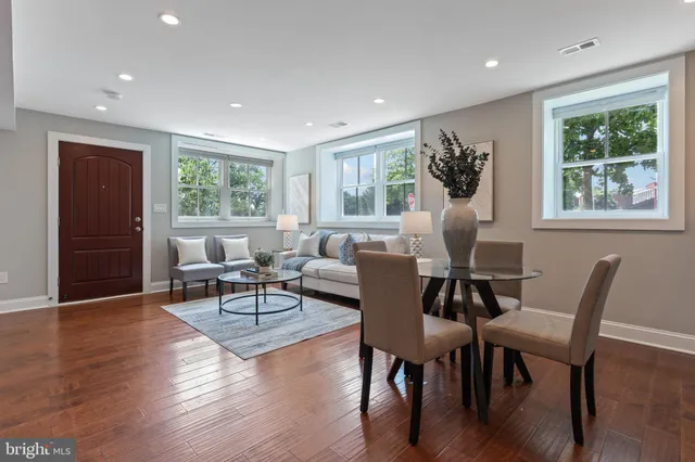 a living room with furniture two window and wooden floor