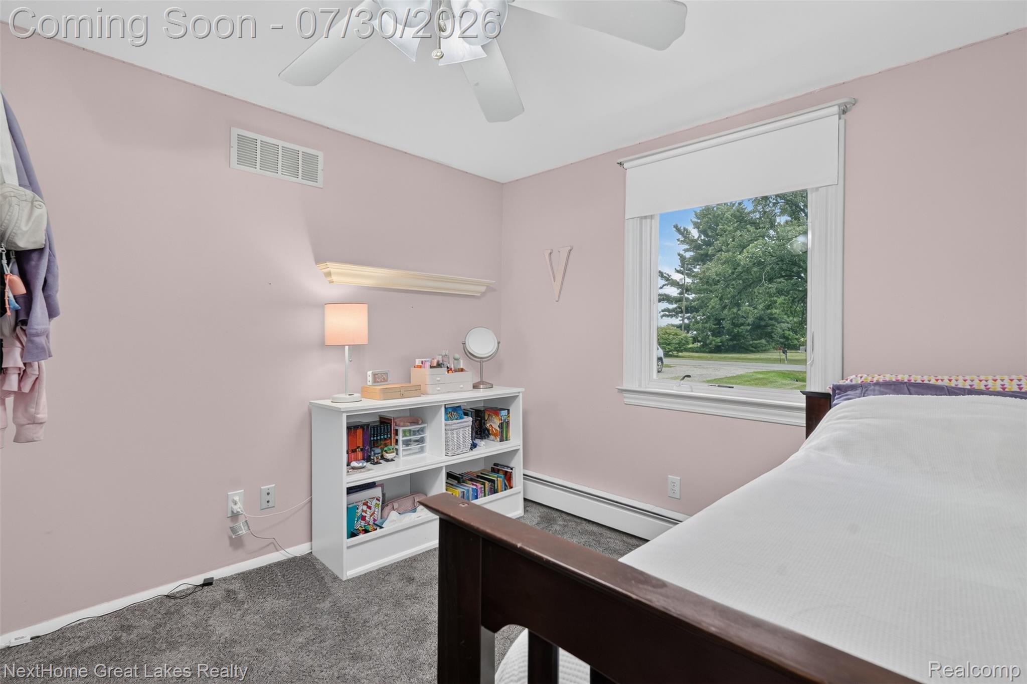 6249 North New Lothrop Road New Lothrop, MI 48460 - Photo 35 of 50 Carpeted room featuring a white ceiling fan, a window with exterior landscaping visible, and a baseboard heating unit