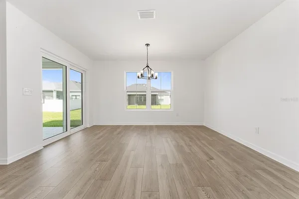 a view of a room with wooden floor a ceiling fan and windows