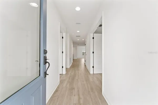 a view of a hallway with wooden floor and a bathroom