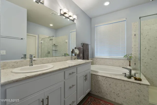 a bathroom with a sink double vanity granite tub shower and a mirror
