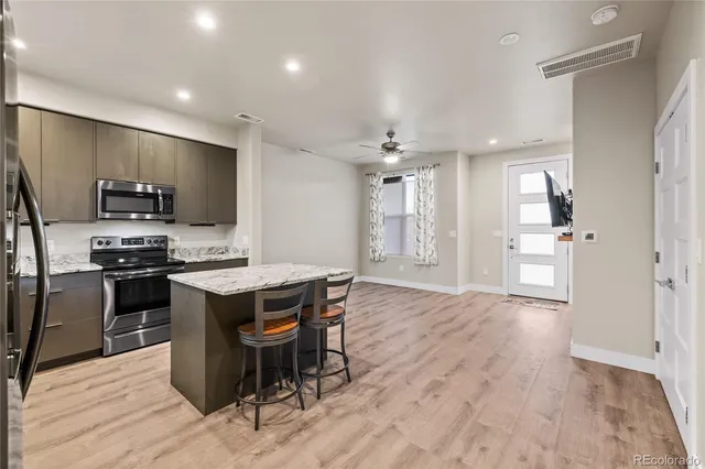 a kitchen with stainless steel appliances kitchen island granite countertop a refrigerator and a stove top oven