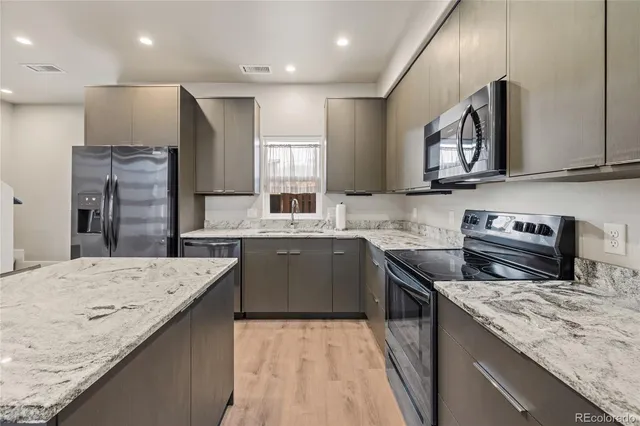a kitchen with stainless steel appliances kitchen island granite countertop a refrigerator and a stove top oven