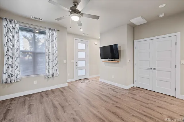 a view of an empty room with wooden floor and a window