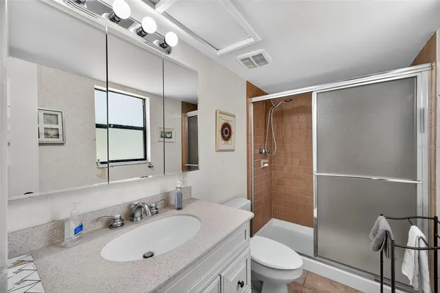 a bathroom with a granite countertop sink toilet a large mirror and shower
