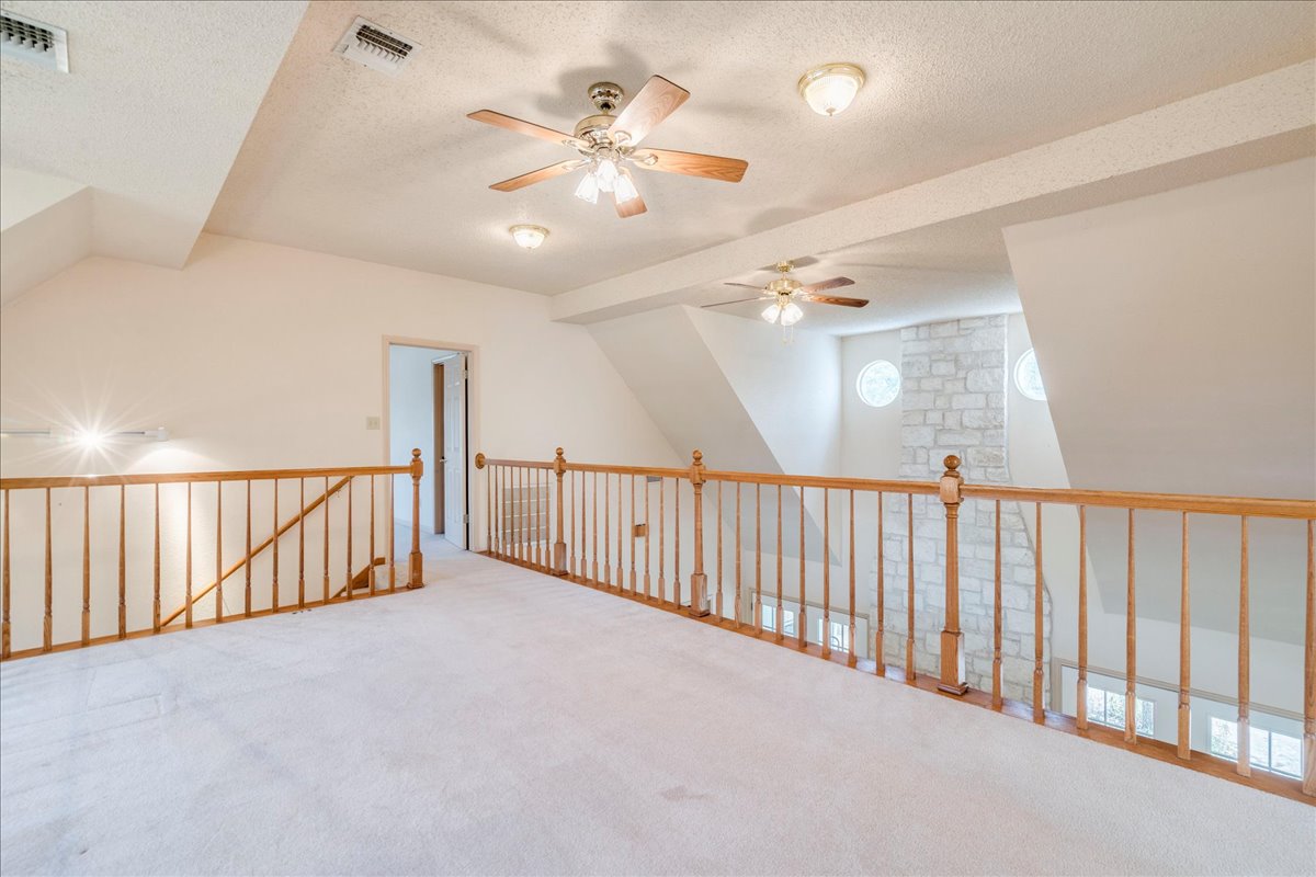 19106 Eyerley Road Manor, TX 78653 - Photo 21 of 40 An airy loft area features light-colored carpet, a wood railing, and an open layout connecting to lower levels.