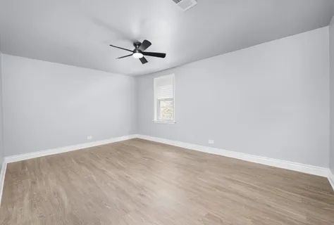 a view of empty room with wooden floor and fan