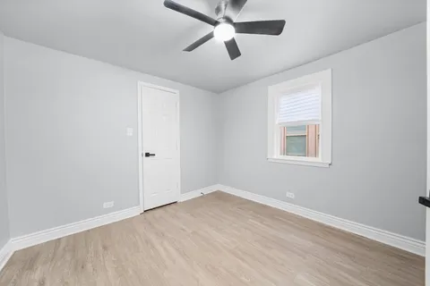 an empty room with ceiling fan and windows