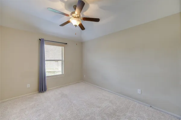an empty room with a ceiling fan and a window