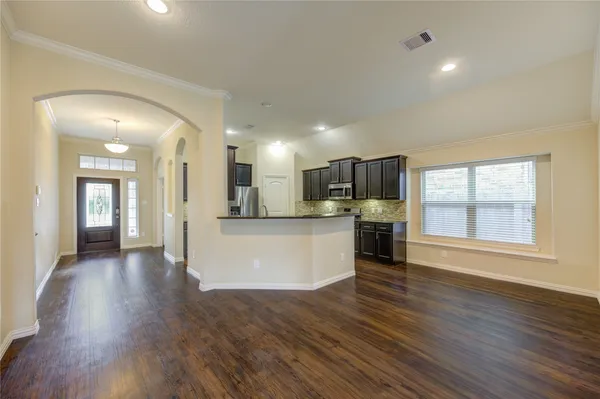 a large kitchen with a center island wooden floor and stainless steel appliances