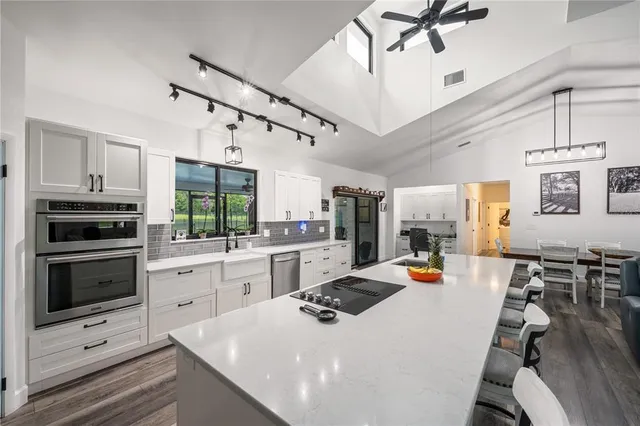 a kitchen with a sink dishwasher a dining table and chairs with wooden floor
