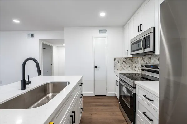 a kitchen with stainless steel appliances granite countertop a sink stove a refrigerator and cabinets