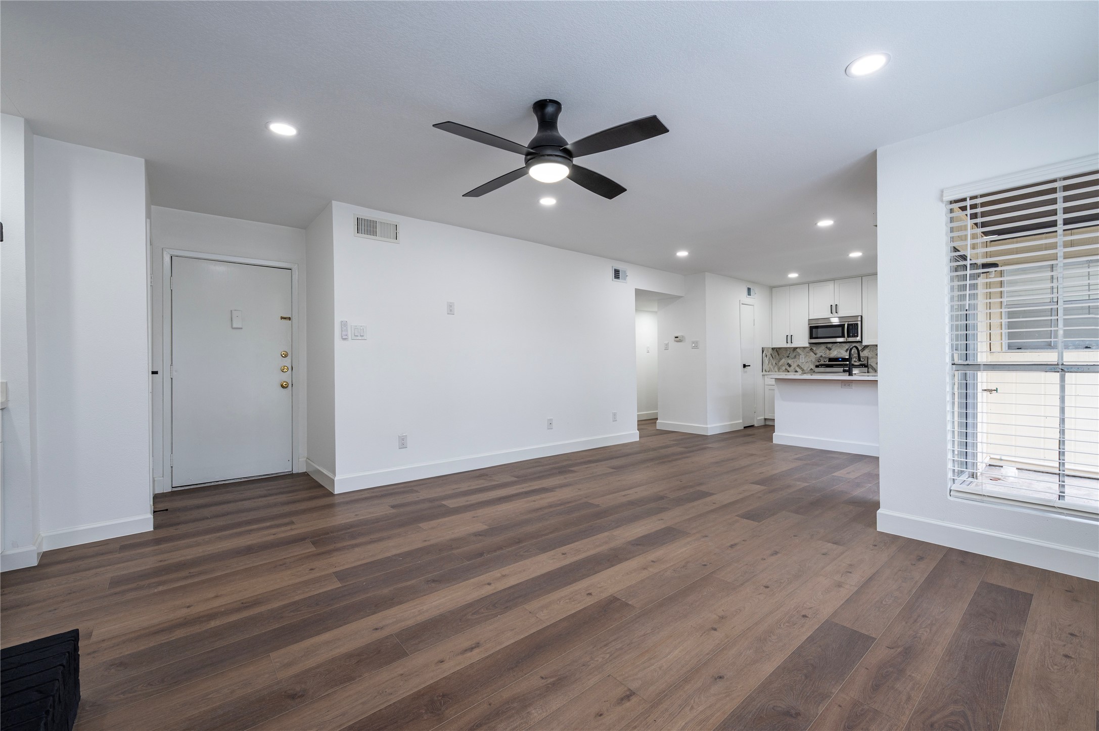 1500 Bay Area Boulevard, Unit 331 Houston, TX 77058 - Photo 6 of 27 an empty room with wooden floor a ceiling fan and kitchen view