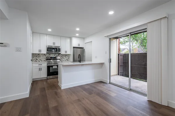 a kitchen with kitchen island wooden floors appliances and cabinets