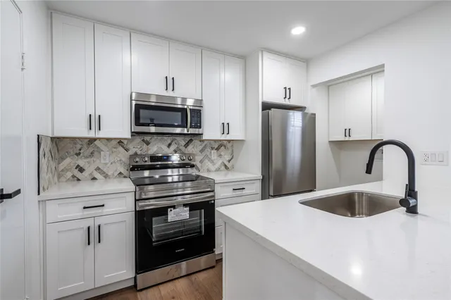 a kitchen with stainless steel appliances granite countertop a stove a refrigerator and a sink