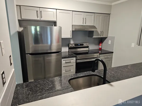 a kitchen with stainless steel appliances granite countertop a refrigerator a stove and a sink