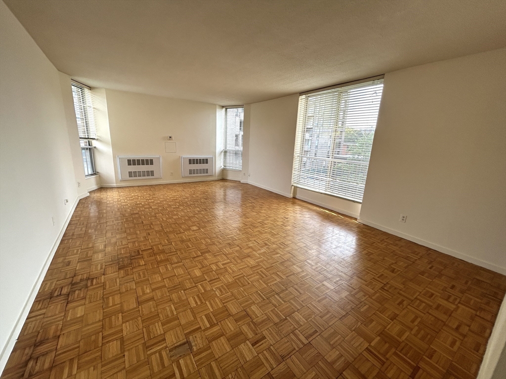 33 Pond Avenue, Unit 401 Brookline, MA 02445 - Photo 3 of 16 wooden floor in an empty room with a window