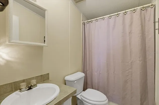 a bathroom with a sink a toilet and shower curtain