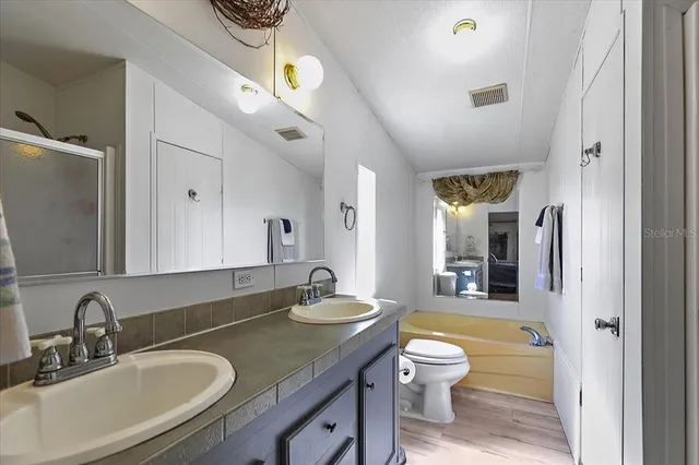 a bathroom with a granite countertop sink a toilet and a large mirror