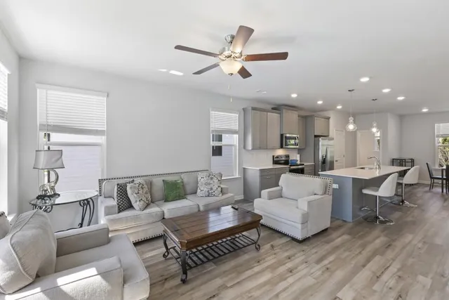 a living room with furniture kitchen view and a chandelier