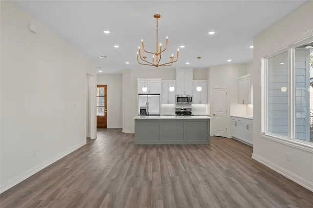 a large kitchen with stainless steel appliances granite countertop a large kitchen island a hardwood floor sink stove and a granite counter top