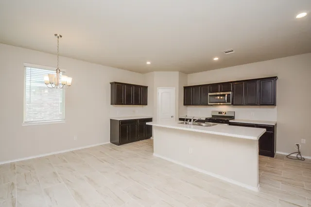 a kitchen with stainless steel appliances a stove top oven a sink a center island and cabinets