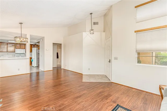 a view of a kitchen with a fridge and wooden floor
