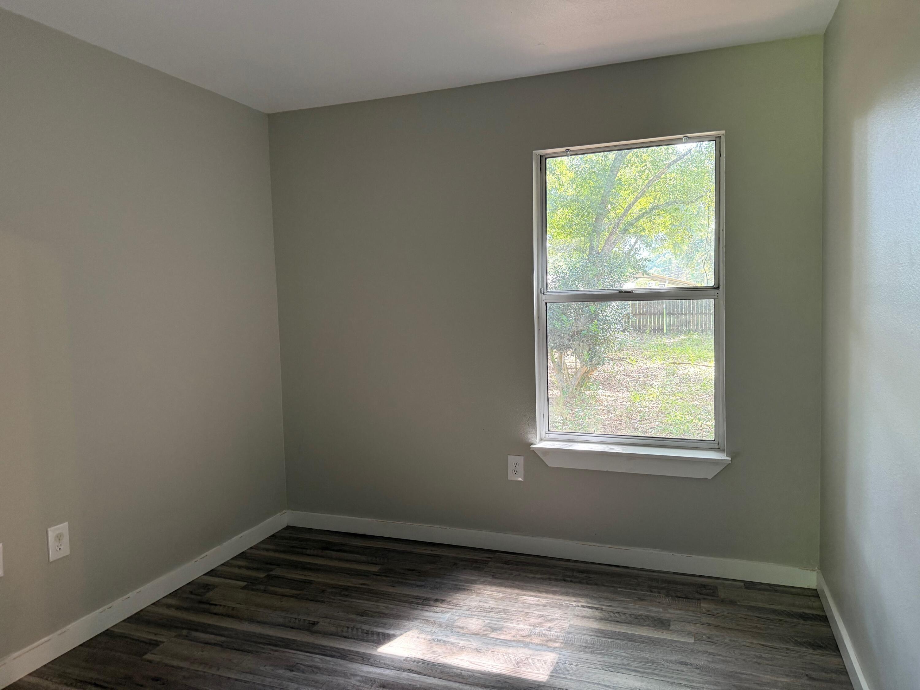 5809 Pinecrest Road Crestview, FL 32539 - Photo 12 of 14 an empty room with wooden floor and windows