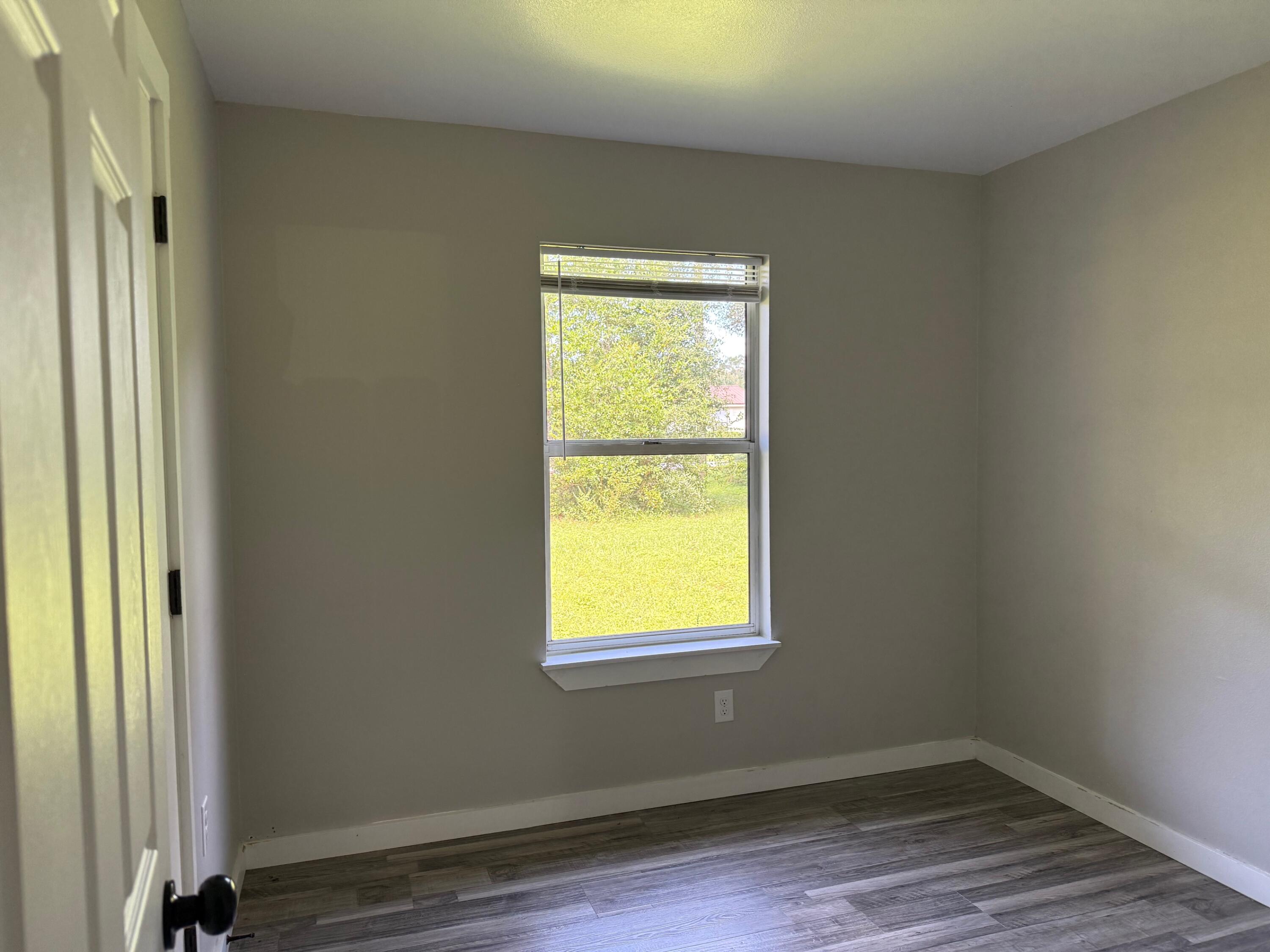 5809 Pinecrest Road Crestview, FL 32539 - Photo 13 of 14 a view of an empty room with wooden floor and a window