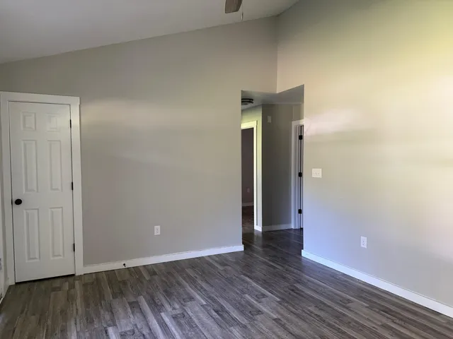 a view of an empty room with wooden floor and closet