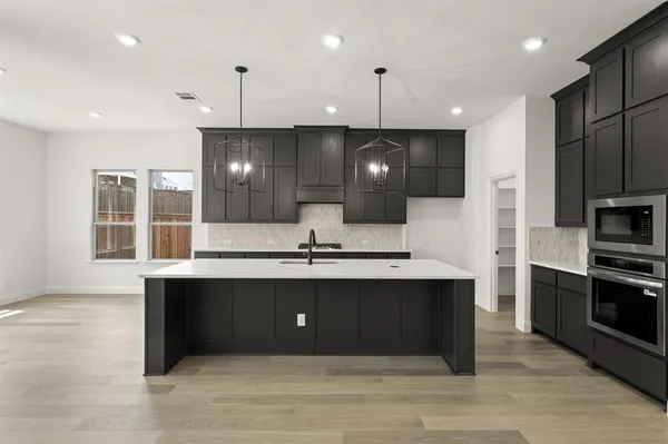 a view of kitchen with stainless steel appliances granite countertop a sink and a refrigerator