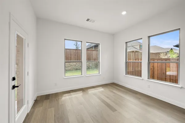 an empty room with wooden floor and windows