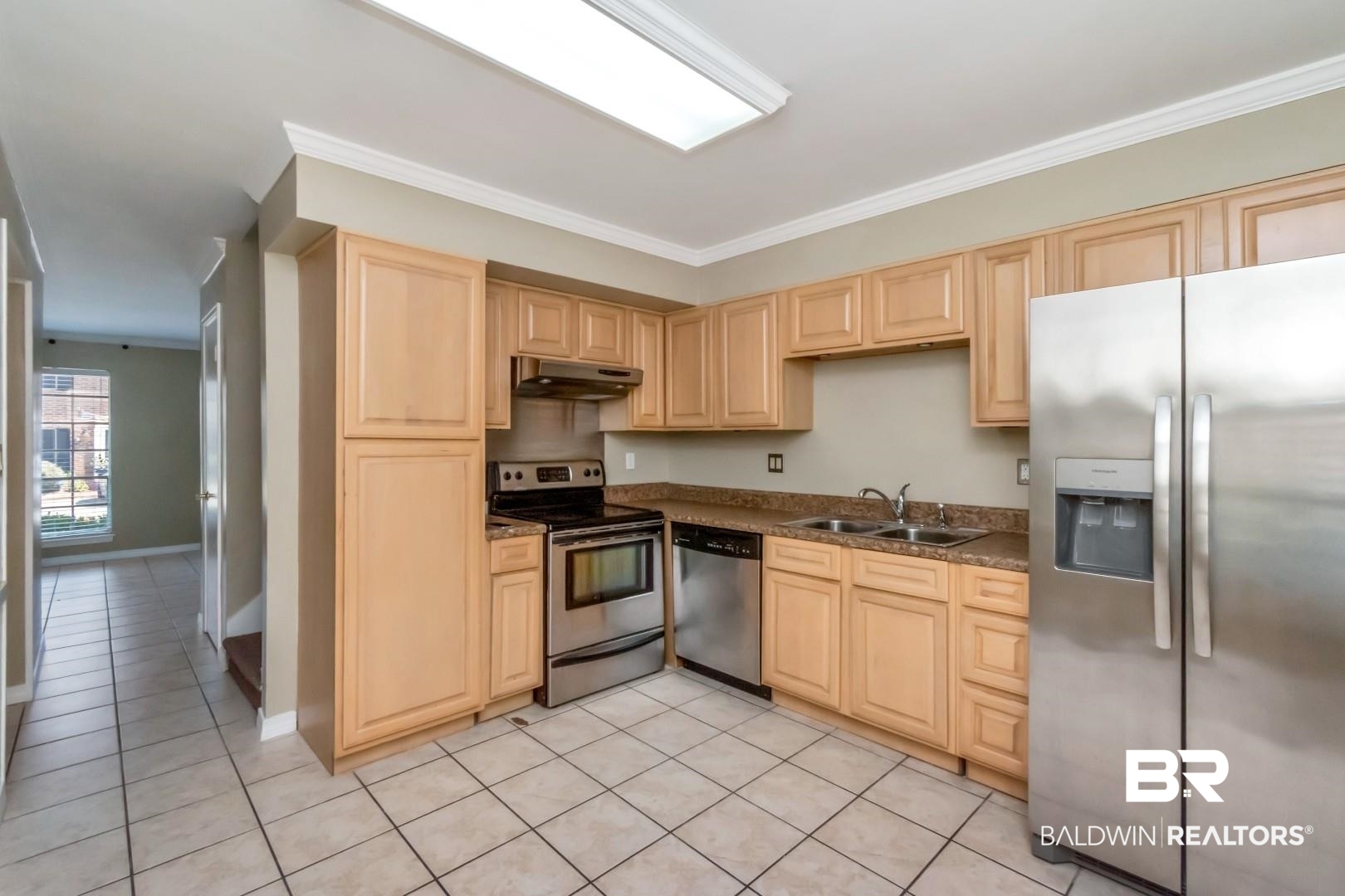 110 Du Rhu Drive, Unit E Mobile, AL 36608 - Photo 8 of 19 Kitchen featuring appliances with stainless steel finishes, light brown cabinets, ornamental molding, light tile patterned floors, and dark countertops
