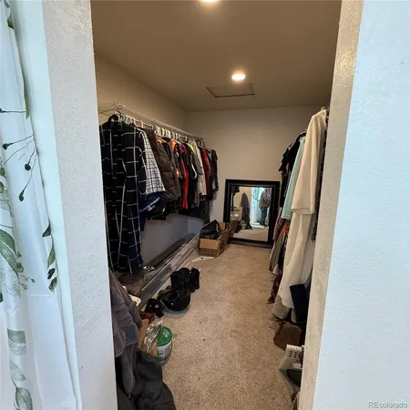 a view of walk in closet with clothes and shoes