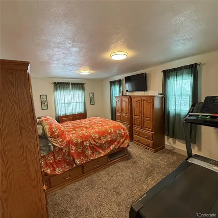 a bed sitting in a spacious bedroom next to a window and dresser