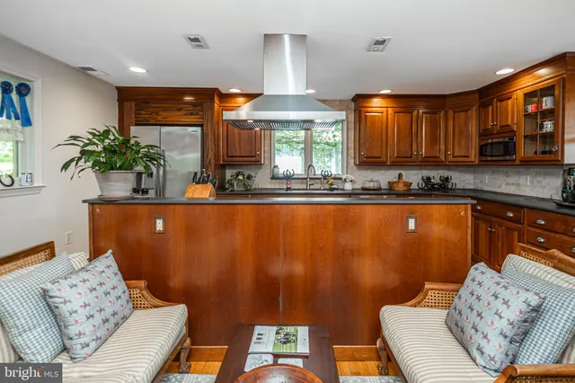 a kitchen with stainless steel appliances granite countertop a sink a stove and a wooden cabinets
