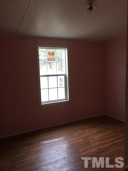660 Ed Thomas Road Cameron, NC 28326 - Photo 3 of 7 an empty room with wooden floor and windows