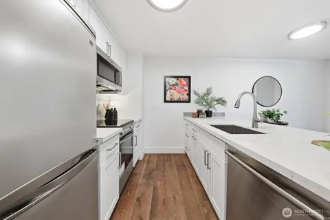a kitchen with a sink dishwasher stove and white cabinets