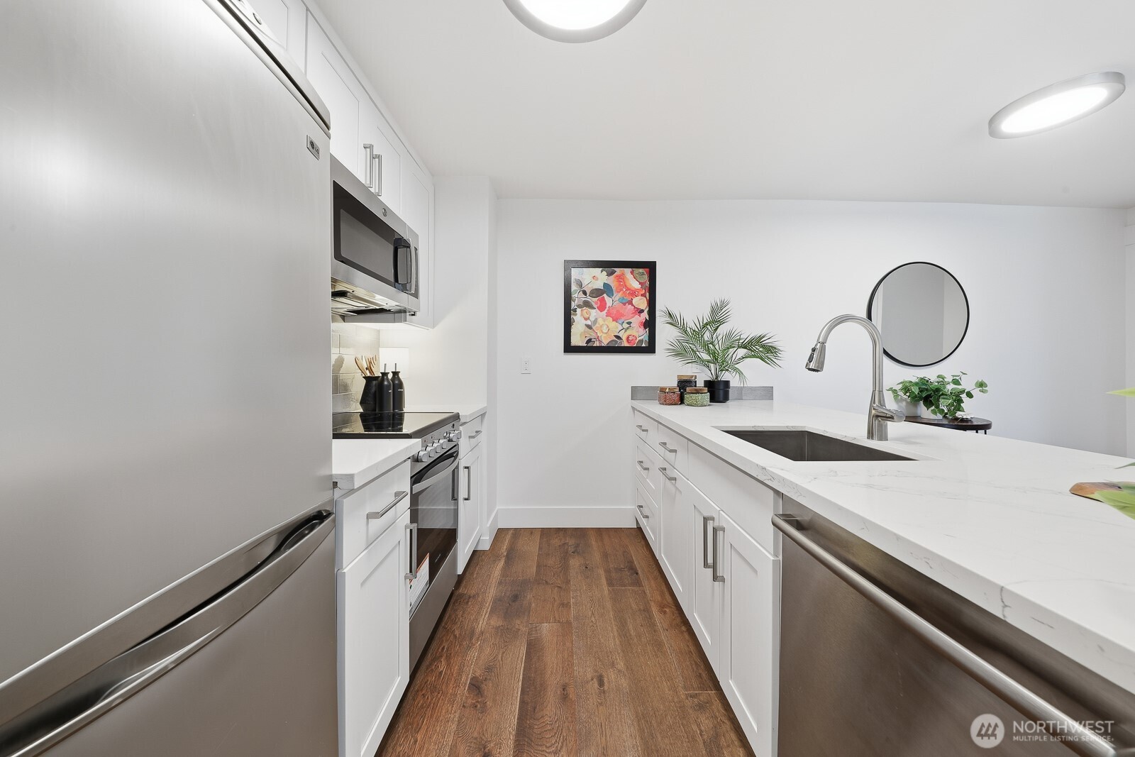 3401 Wallingford Avenue North, Unit 408 Seattle, WA 98103 - Photo 5 of 15 a kitchen with a sink dishwasher stove and white cabinets
