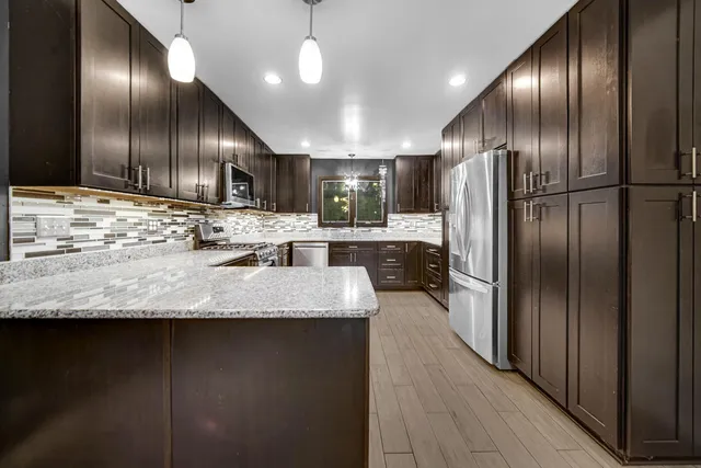 a kitchen with stainless steel appliances granite countertop a stove a refrigerator and a sink