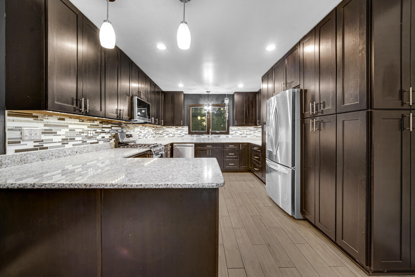 6747 West 450 Road North Michigan City, IN 46360 - Photo 17 of 37 a kitchen with kitchen island granite countertop wooden cabinets a refrigerator and a sink