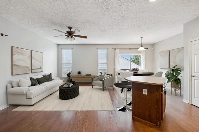 a living room with furniture a large window and wooden floor