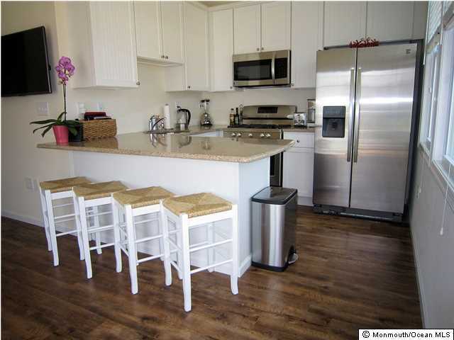 3305 Seaview Road Lavallette, NJ 08735 - Photo 5 of 13 a kitchen with stainless steel appliances granite countertop a refrigerator a stove top oven a sink dishwasher and white cabinets with wooden floor
