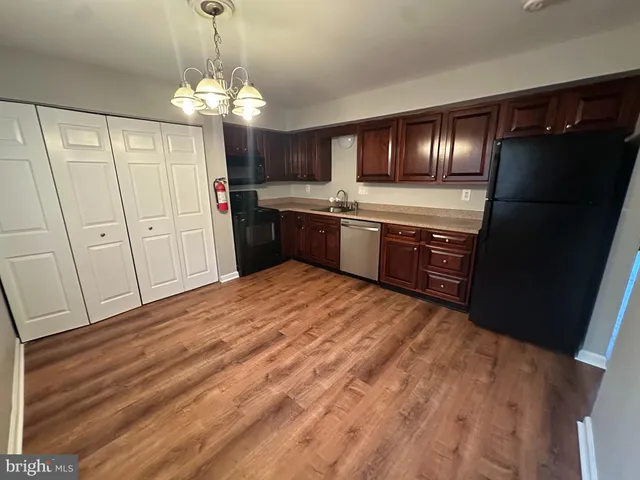 a large kitchen with granite countertop a refrigerator and a wooden floor