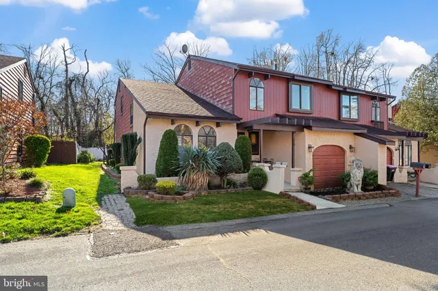 a front view of a house with garden and trees